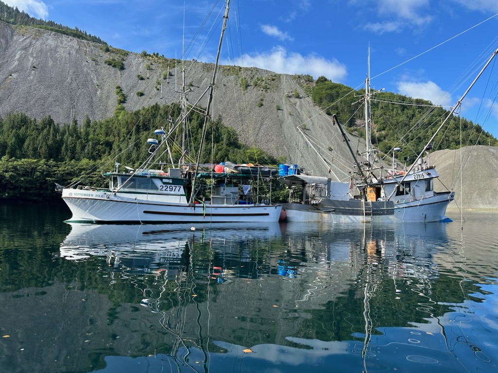 Two fishing vessels moored in a quiet BC inlet surrounded by forested mountains